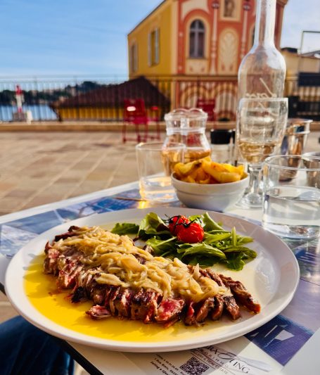 Contre-filet de boeuf avec fondue d'échalottes Contre-filet de bœuf fondue d’échalotes servi en terrasse au restaurant Le Cosmo à Villefranche-sur-Mer